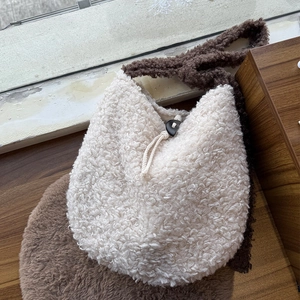 Close-up of plush cream faux fur bag featuring brown adjustable strap and drawstring closure
