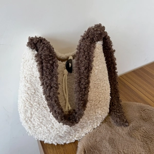 Close-up of fluffy cream plush tote bag with dark brown contrast piping and toggle closure