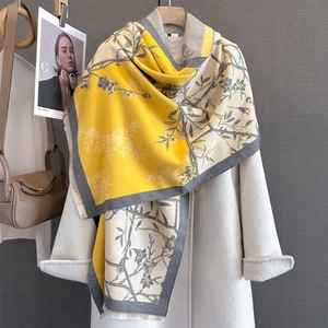 Detail of floral print scarf with fringe edges draped over a white wool coat