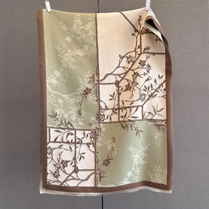 Detail view of woven cashmere-feel scarf with oriental plum blossom pattern and fringe edges