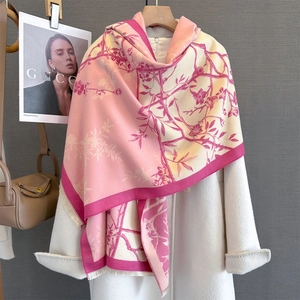 Detail of pink floral cashmere feel scarf with fringe on a white wool coat