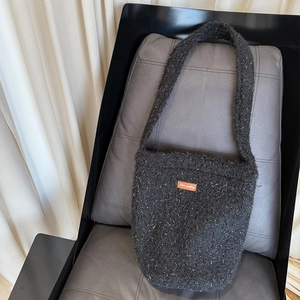 Detail of grey plush bucket bag featuring sparkling texture and Star-picking leather patch