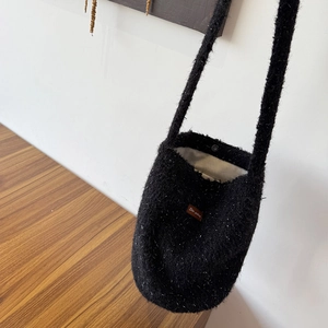 Detail of black fuzzy bucket bag showing soft faux fur texture and magnetic snap closure