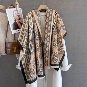 Close-up of paisley pattern pashmina shawl with tassel fringe on a white coat