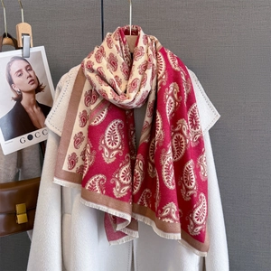 Elegant red and white paisley print scarf with fringe hanging on a white wool coat