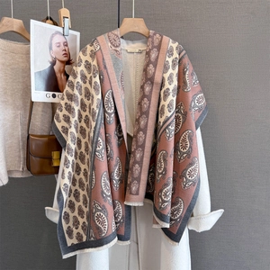 Close-up of bohemian paisley cashmere shawl with fringe detail on a white coat