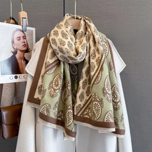 Detailed macro view of sage green paisley cashmere shawl with delicate tassel fringe