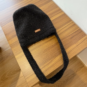 Sparkly black plush bucket bag with glitter yarn and leather logo on wooden background