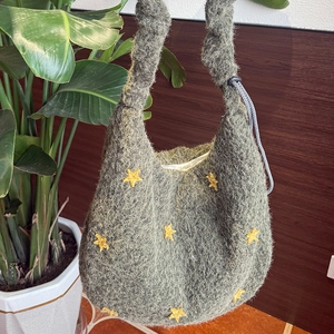 Detail der grünen Stricktasche mit gelbem Sternmuster und geknotetem Griff