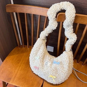 Détail du sac en peluche crème avec des mini nœuds colorés et une texture douce effet mouton
