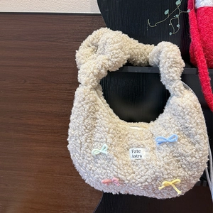 Détail d'un cabas en peluche avec des nœuds colorés et un écusson logo brodé