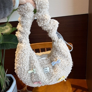 Détail du sac cabas en peluche crème avec nœuds tissés colorés et étiquette de la marque