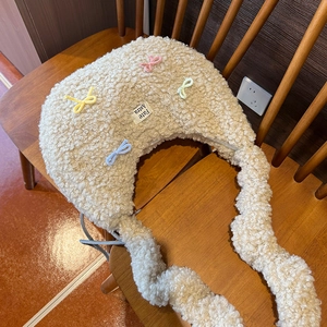 Détail du sac fourre-tout en peluche beige avec nœuds colorés et bandoulière à volants