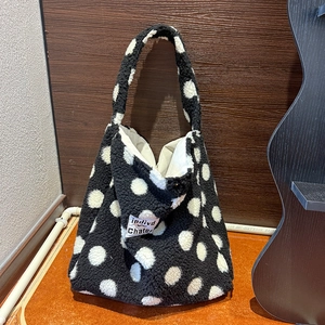 Vista ravvicinata della borsa tote in peluche a pois neri e bianchi con logo