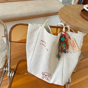 Minimalist canvas tote bag with red dog embroidery on a stylish amber folding chair