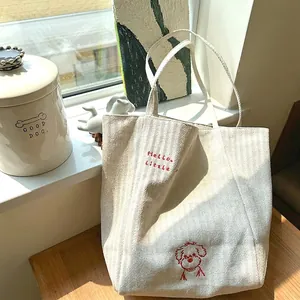 Canvas tote bag with red dog embroidery and Hello little text in soft sunlight