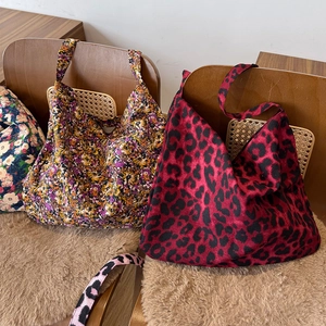 Vue détaillée de grands sacs fourre-tout à imprimé léopard et fleurs sur chaise