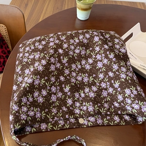 Détail d'un sac bandoulière en toile florale avec boucle magnétique dans un café