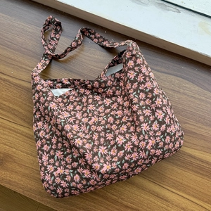 Détails du tissu en toile florale et des coutures sur le sac bandoulière marron