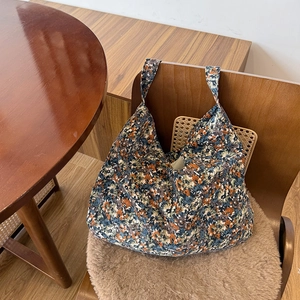 Détail d'un sac cabas en toile fleurie suspendu à une chaise dans un décor chaleureux