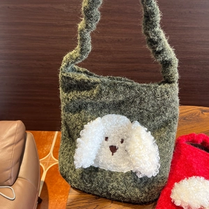 Detail of dark green plush knit tote bag with 3D white dog head and spiral handle