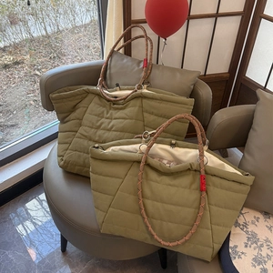 Detail of olive green quilted tote bag with braided rope handles and nylon texture