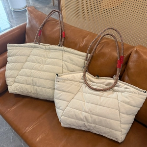 Detail of quilted cloud tote bag featuring thick rope handles and plush beige fabric texture