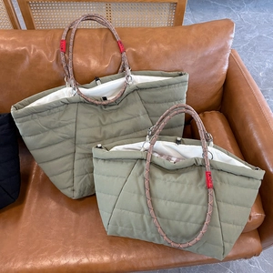 Detailed comparison of two green quilted tote bags on a sofa showing sizes and rope handles
