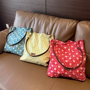 Close-up of vintage floral tote bags in blue, yellow, and red on a leather sofa