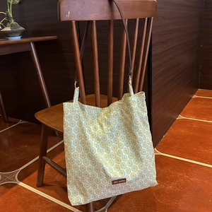 Close-up of vintage floral canvas tote bag hanging on a wooden chair with brand tag