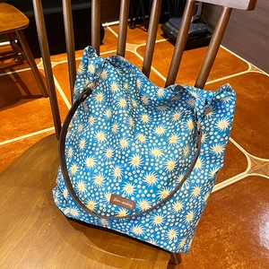 Close-up of floral canvas tote bag with Star-picking leather tag on a vintage wooden chair