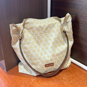 Close-up of floral tote bag with blue sunflower pattern and leather strap detail