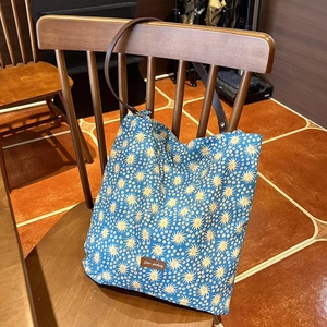 Floral shoulder bag with yellow star patterns hanging on a vintage wooden chair