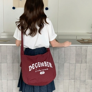 Détail du sac à bandoulière en nylon bordeaux avec inscription graphique December 1996