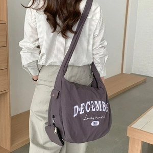 Détail du sac bandoulière en nylon gris avec imprimé DECEMBER et petite pochette amovible