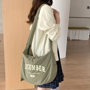 Détail du sac à bandoulière en nylon vert armée avec lettrage blanc style vintage