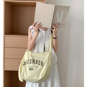 Détail du sac fourre-tout en nylon jaune clair avec lettrage brun pour un style décontracté