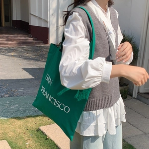 Close-up of green nylon shoulder bag with white San Francisco letter print in casual style