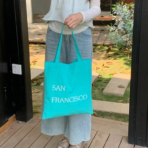 Outdoor shot of mint green nylon shoulder bag with San Francisco lettering print