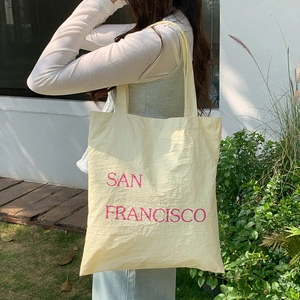 Detail of minimalist nylon tote bag with pink San Francisco print and textured fabric