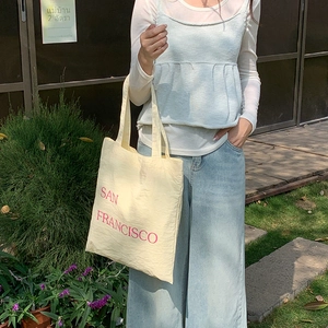 Detail of beige nylon tote bag with red San Francisco lettering in casual outdoor setting