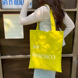Detail of yellow nylon tote bag with San Francisco lettering and wide shoulder strap