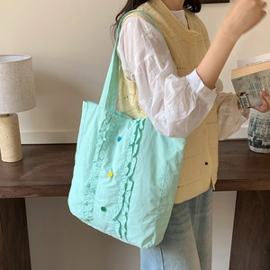 Détail du sac cabas en nylon vert menthe avec bords à volants et boutons colorés