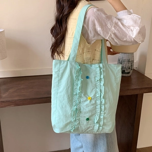 Détail du sac cabas en nylon vert menthe avec bords volantés et boutons colorés