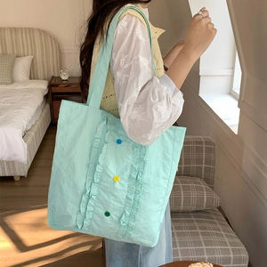 Détail du sac cabas en nylon vert menthe avec volants décoratifs et boutons colorés sur le côté