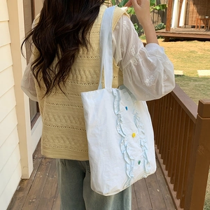 Détail du sac à épaule en nylon bleu avec bordure à volants et boutons colorés
