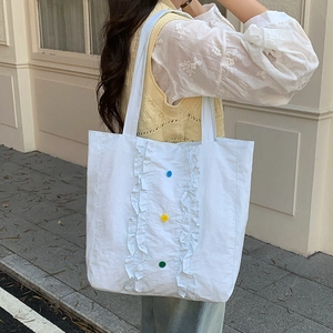 Détail de bordures à volants et boutons colorés sur un grand sac cabas en nylon