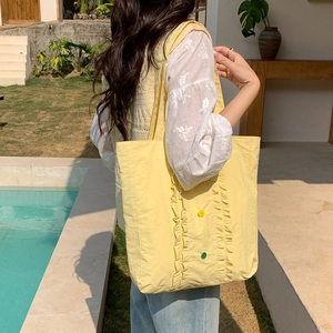 Détail d'un sac cabas en nylon jaune pâle avec bords à volants et boutons colorés