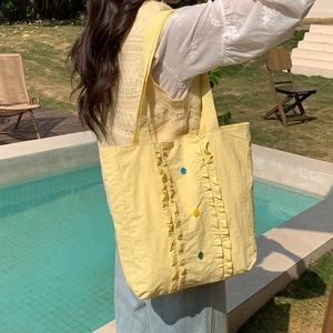 Détail de volants et boutons colorés sur un sac fourre-tout en nylon jaune citron