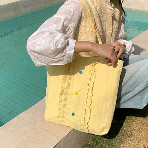 Détail du sac cabas en nylon jaune avec bordures à volants et accents de boutons colorés